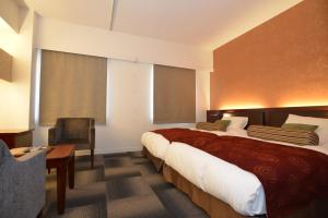 una habitación de hotel con 2 camas y una silla en Yamato Kashihara City Hotel, en Kashihara