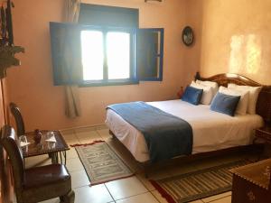 una camera con letto, finestra e sedia di Essaouira Wind Palace a Essaouira