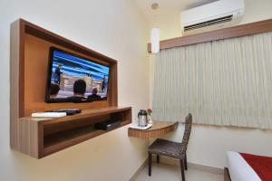 a hotel room with a tv and a table and a chair at La Sara Comforts in Bangalore