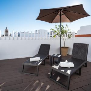 two chairs and a table with an umbrella on a roof at Welldone Antiquarium in Seville