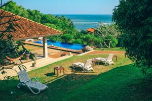 a yard with chairs and a pool and a house at Highland Villa in Weligama