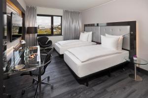 a hotel room with two beds and a desk at INNSiDE by Meliá Wolfsburg in Wolfsburg