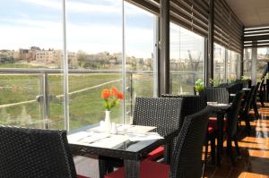 Olive Hotel Amman في عمّان: غرفة طعام مع طاولات وكراسي ونوافذ