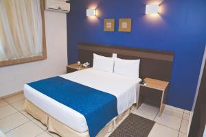 a bedroom with a large bed with a blue wall at Comfort Hotel Araraquara in Araraquara