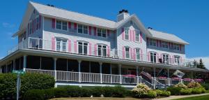 une grande maison blanche avec volets roses dans l'établissement Harbor House Inn, à Grand Haven