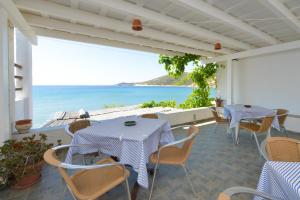 a patio with tables and chairs and a view of the ocean at Cyclades Beach Apartments in Platis Gialos