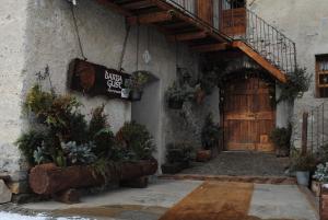 un ingresso a un edificio con una porta in legno e piante di Agriturismo Barba Gust a Cesana Torinese