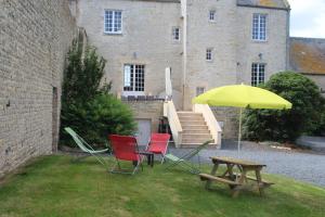 a table and chairs and an umbrella in front of a building at Domaine de La Ramée in Trévières