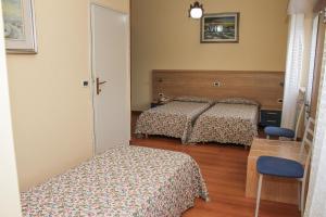 a bedroom with two beds and a table and a chair at Al Ponte della Vittoria in Belluno