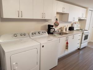a white kitchen with white cabinets and a sink at Gite La Ptite Falaise hébergement touristique in Sainte-Anne-des-Monts