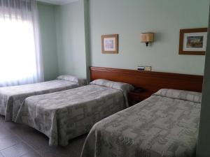 Habitación con 2 camas y ventana en Hotel Avenida, en Gijón