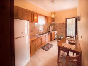 a kitchen with wooden cabinets and a white refrigerator at Antigoni House in Póros Kefalonias