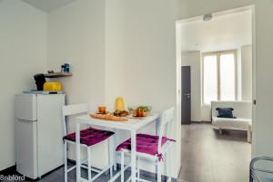 uma cozinha com uma mesa branca e dois bancos em Appartement Place Kléber em Estrasburgo