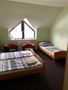 two beds in a room with a window at Penzion Tetřívek in Nové Hutě