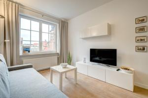 a white living room with a tv and a couch at Apartament 6 Old Town in Gdańsk