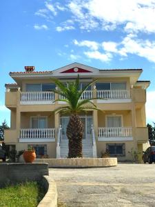 a large house with a palm tree in front of it at Villa Korais Luxury 3br apt with sea view in Thessaloniki