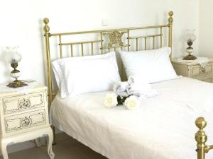 Una cama blanca con sábanas blancas y flores. en Villa Korais Luxury 3br apt with sea view, en Tesalónica