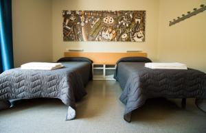 バルセロナにあるアルベルグ ペレ タレスのベッド2台が備わる客室で、壁には絵画が飾られています。
