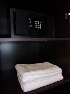 un horno microondas con una pila de toallas en un estante en Demetrio Hotel Apart en Olavarría