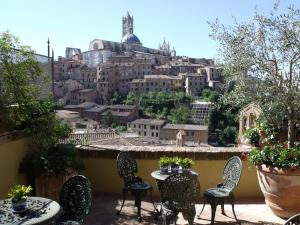 a balcony with chairs and tables and a view of a city at Residenza d'Epoca Campo Regio Relais in Siena