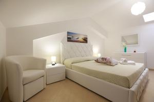 ein weißes Schlafzimmer mit einem Bett und einem Stuhl in der Unterkunft Casa Vacanza Il Dromone in Pozzallo