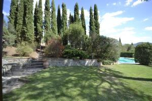 een tuin met een gazon, bomen en een zwembad bij Appartamento Valentina in Cortona