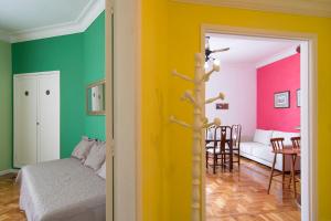 a room with a bed and a living room with colorful walls at Flat Imperador in Petrópolis