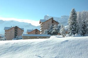 a snow covered hill with buildings in the background at ANCOLIE 23 Les Chalets de Super D in Le Dévoluy