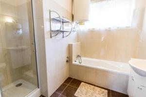 シオーフォクにあるLeander Apartmanのバスルーム(シャワー、バスタブ、シンク付)