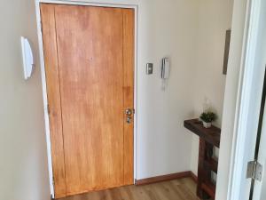 una puerta de madera en una habitación con suelo de madera en Departamento completo 35 mts2 - 1 hab y 1 futón - Centro Tomé - 3 personas max - Edificio Don Francisco, en Tomé