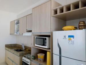 cocina con nevera blanca y microondas en Recanto da Orla - apartamento lindo e aconchegante - 2 Quartos, en Porto Seguro