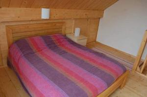 Cama en una cabaña de madera con manta a rayas en Bungalow, en Froidchapelle