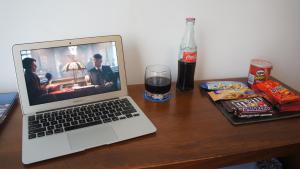 a laptop computer sitting on a wooden table with a drink at Palm Beach Plaza Hotel in Montevideo