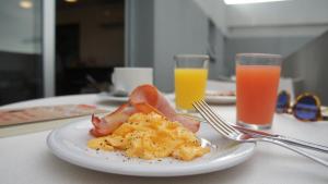 a plate of food on a table with two glasses of orange juice at Palm Beach Plaza Hotel in Montevideo