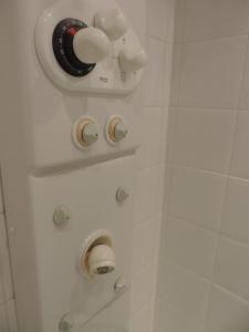 una ducha con tres perillas en una pared blanca en chambre single avec breakfast, en Cannes