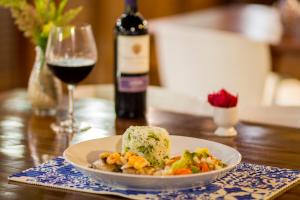 a plate of food on a table with a glass of wine at Kristie Resort Natal Hotel in Natal