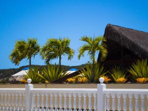 a white fence in front of a house with palm trees at Kristie Resort Natal Hotel in Natal