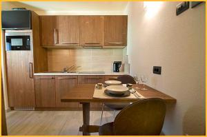 eine kleine Küche mit einem Holztisch und Stühlen in der Unterkunft Appartamento Jek in Livigno