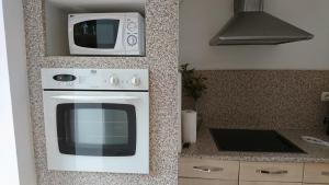a microwave sitting on top of a stove in a kitchen at Le Jardinet in Pont-Sainte-Maxence