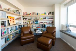 a library with two chairs and a table and bookshelves at The Study at University City, Study Hotels in Philadelphia
