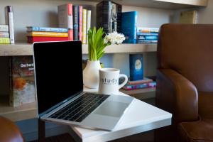 a laptop computer sitting on a table with a coffee mug at The Study at University City, Study Hotels in Philadelphia