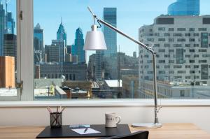 a desk with a lamp on a desk in front of a window at The Study at University City, Study Hotels in Philadelphia