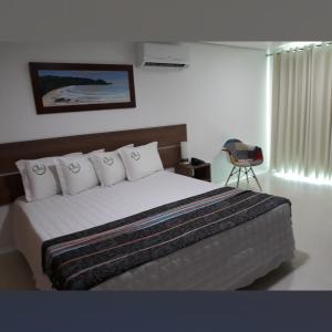um quarto com uma cama com lençóis brancos e almofadas em Pousada Gaia em Macaé