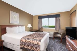 a hotel room with a bed and a flat screen tv at Baymont by Wyndham Columbus/Rickenbacker in Columbus