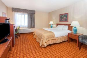 a hotel room with a bed and a television at Baymont by Wyndham Detroit/Roseville in Roseville