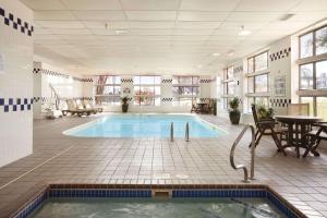 a large swimming pool in a room with a table and chairs at Baymont by Wyndham Sioux Falls in Sioux Falls