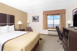 a hotel room with a bed and a desk and a window at Baymont by Wyndham Green Bay in Green Bay