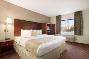 スーフォールズにあるBaymont by Wyndham Sioux Fallsの大きなベッドと窓が備わるホテルルームです。
