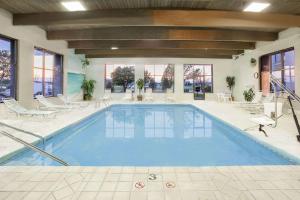 a large swimming pool in a building with chairs at Baymont by Wyndham Janesville in Janesville