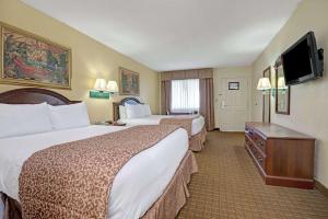 a hotel room with two beds and a flat screen tv at Travelodge by Wyndham Montgomery East in Montgomery